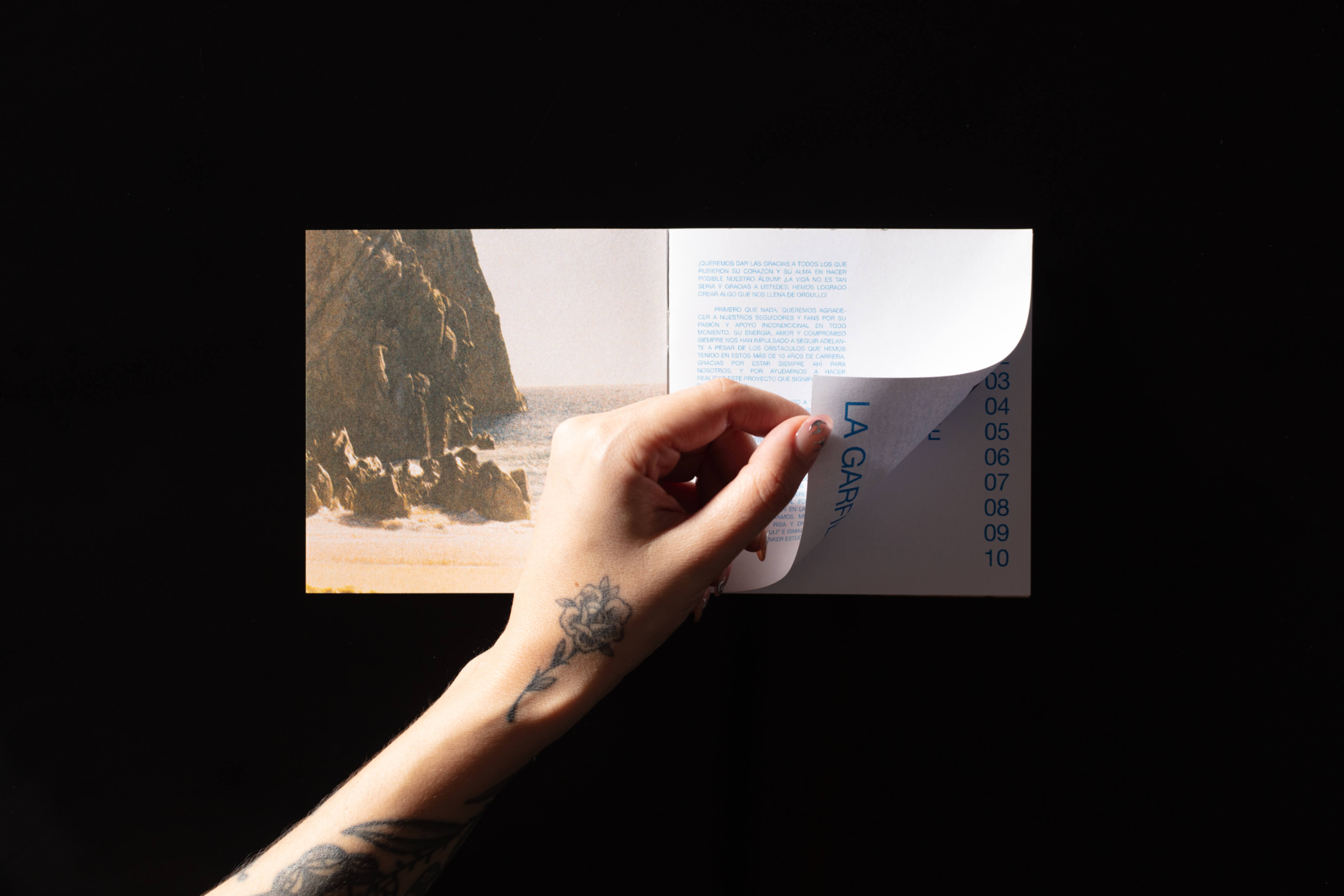 Person flipping through La Garfield’s album booklet over black background.