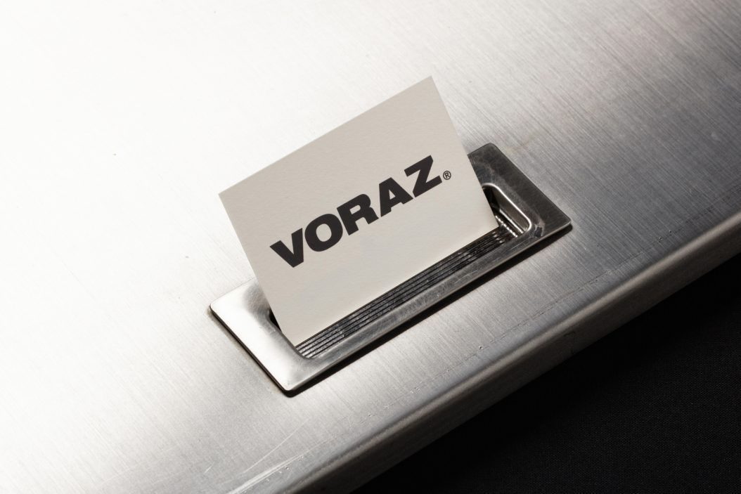 Voraz brand card with clean design on metallic surface.