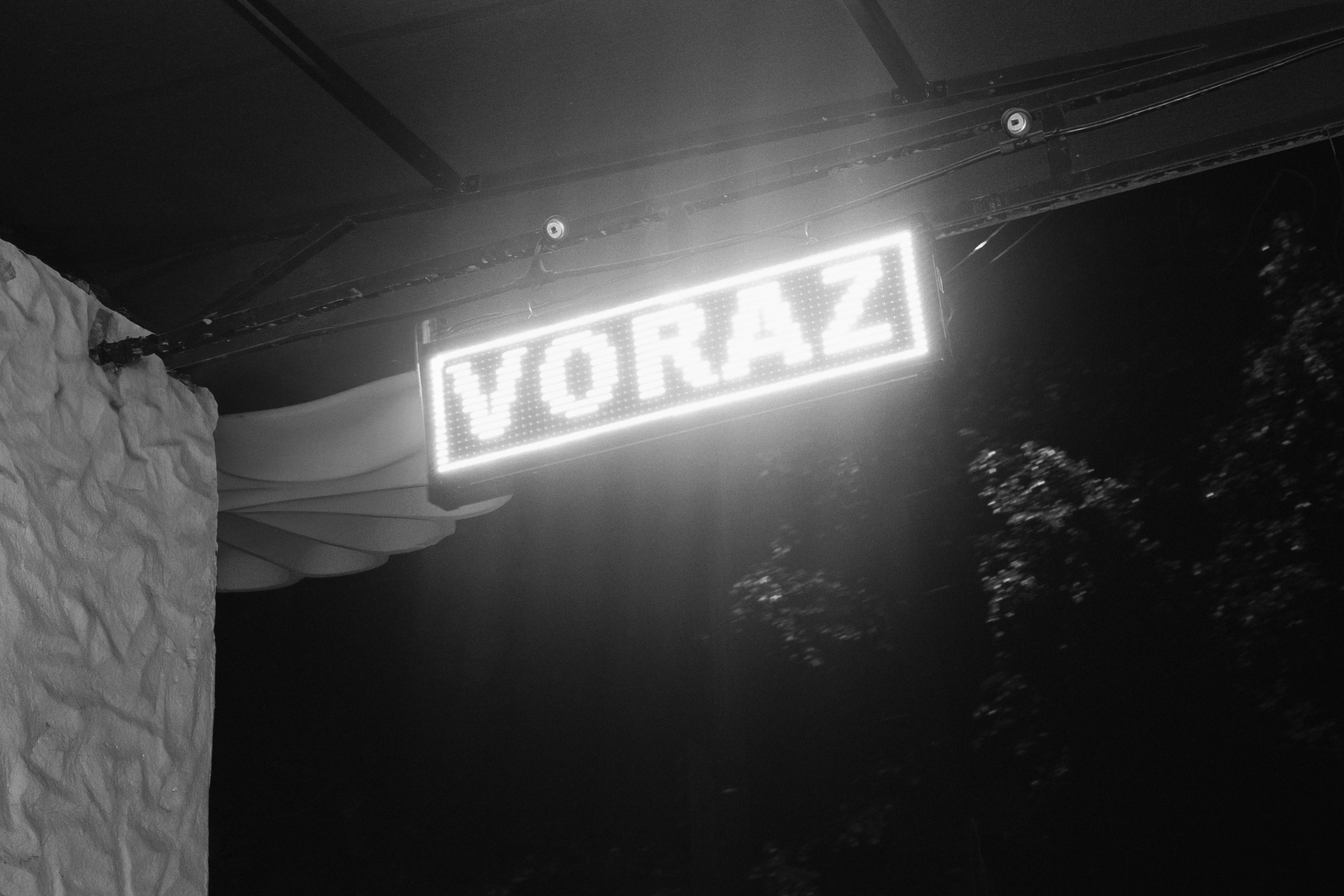Illuminated LED signage featuring Voraz wordmark on outside wall.