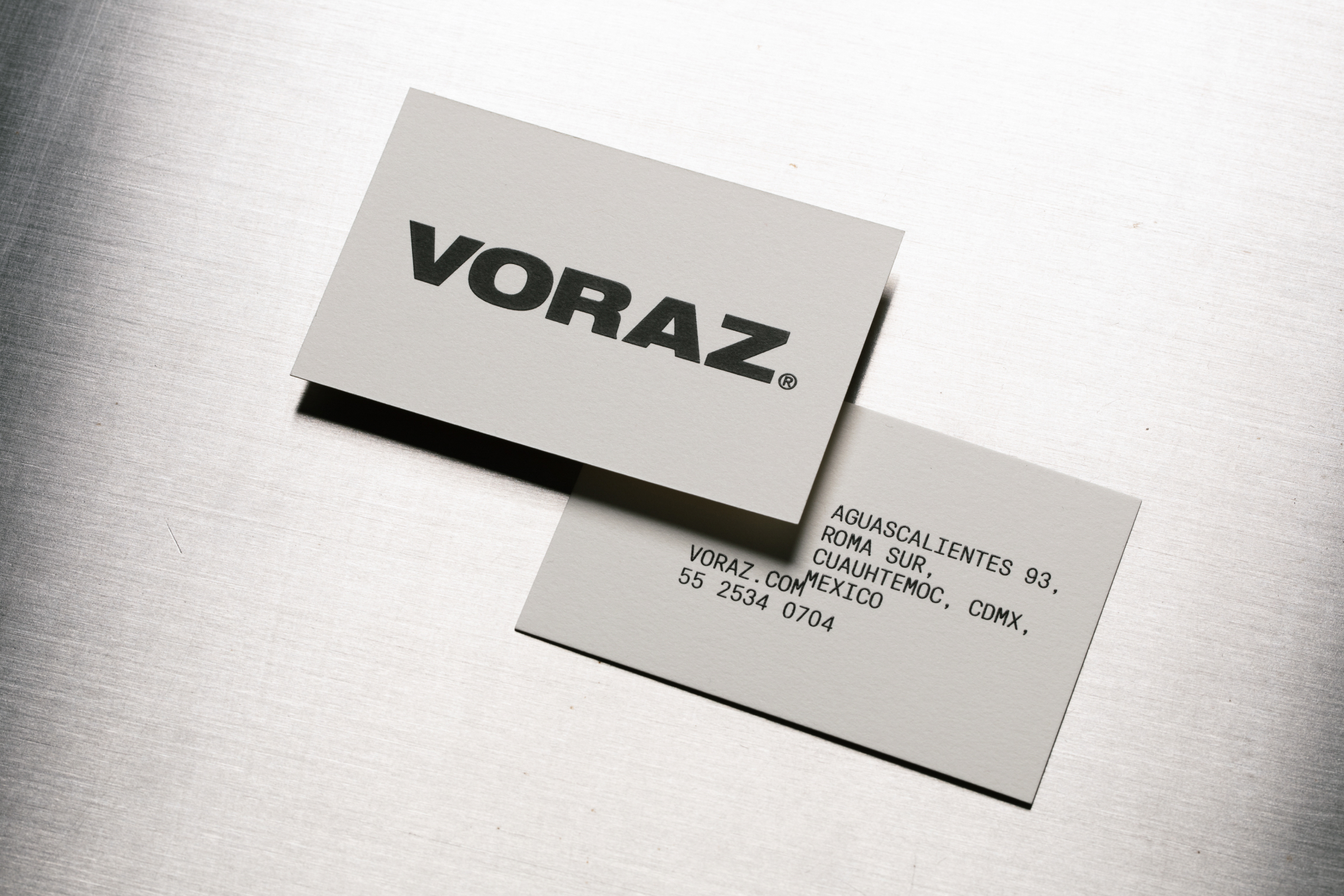 Voraz brand card with clean design on metallic surface.