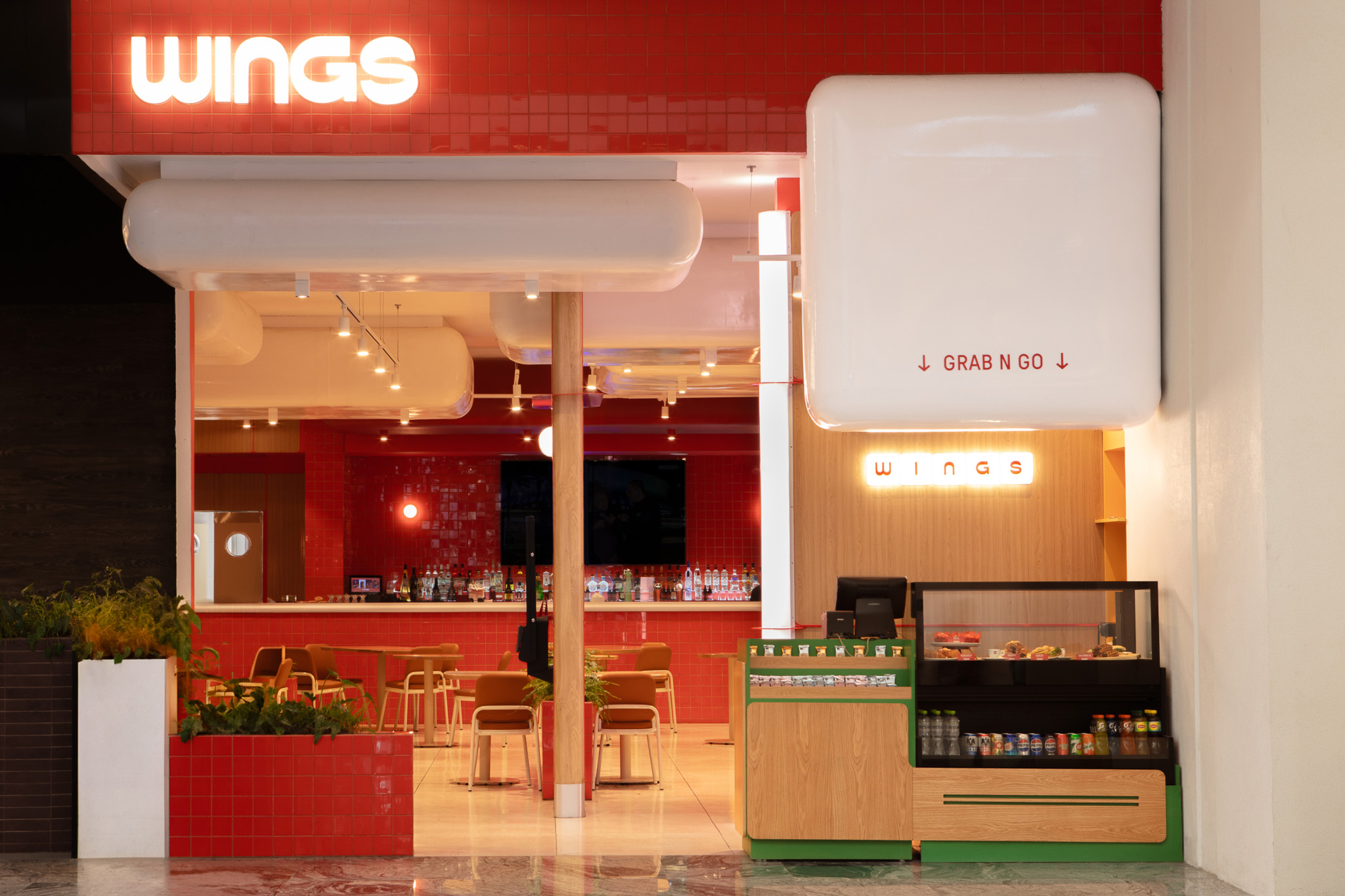 Wings restaurant facade with red and wood tones, grab-and-go area and bar in the background.