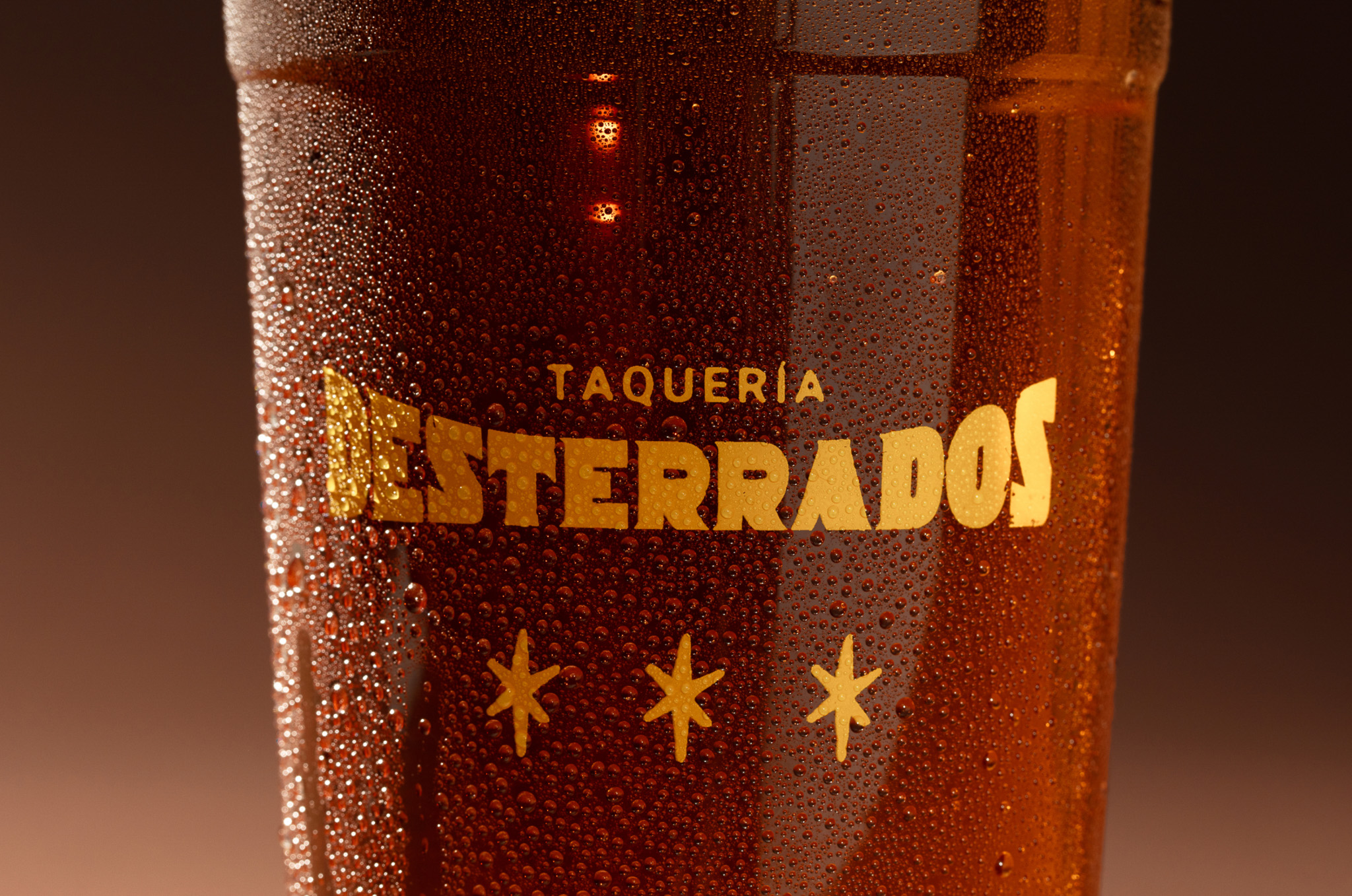 Close-up view of Taquería Desterrados wordmark on plastic cup.